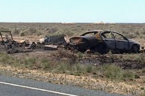 Shows burned out car on side of road on Sturt Highway